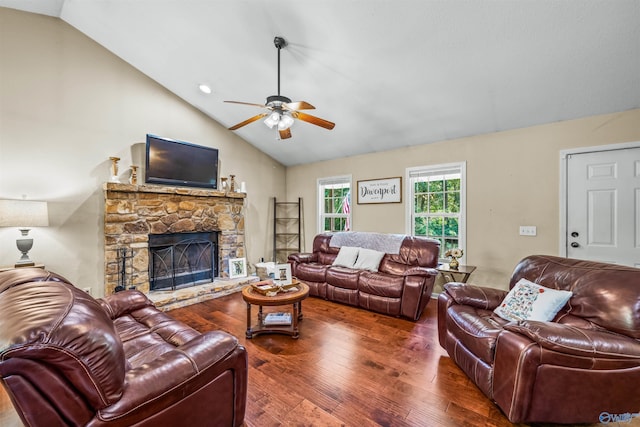 living room with a stone fireplace, dark wood-type flooring, vaulted ceiling, and ceiling fan