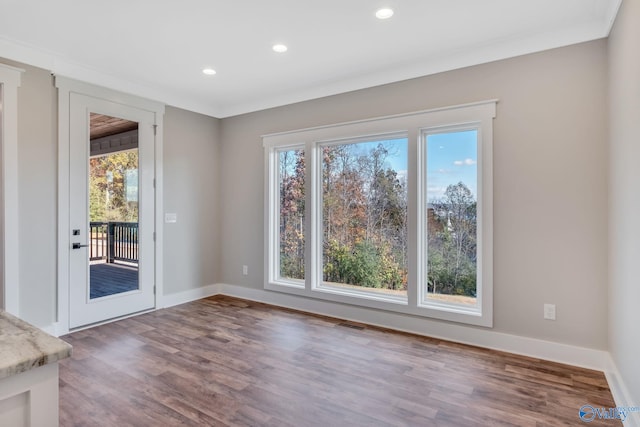 unfurnished dining area with hardwood / wood-style flooring, plenty of natural light, and ornamental molding