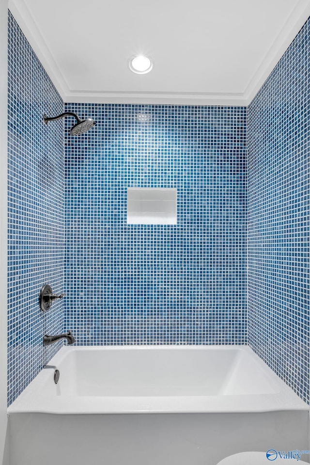 bathroom featuring ornamental molding, tiled shower / bath combo, and toilet