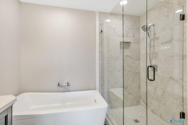 bathroom featuring vanity and independent shower and bath