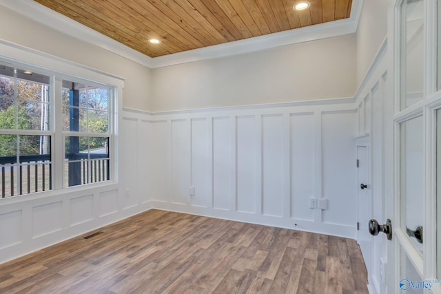 spare room featuring wood-type flooring, ornamental molding, and wood ceiling