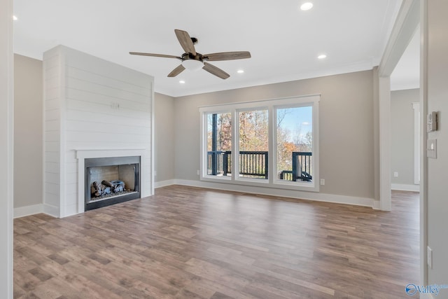 unfurnished living room featuring a large fireplace, ceiling fan, hardwood / wood-style floors, and crown molding