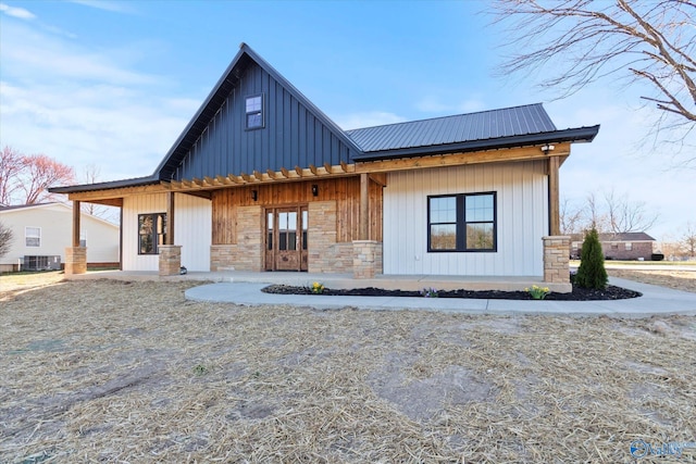 view of front of home with stone siding, central AC, metal roof, and board and batten siding