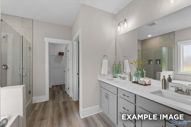 bathroom featuring wood-type flooring, dual bowl vanity, and plus walk in shower