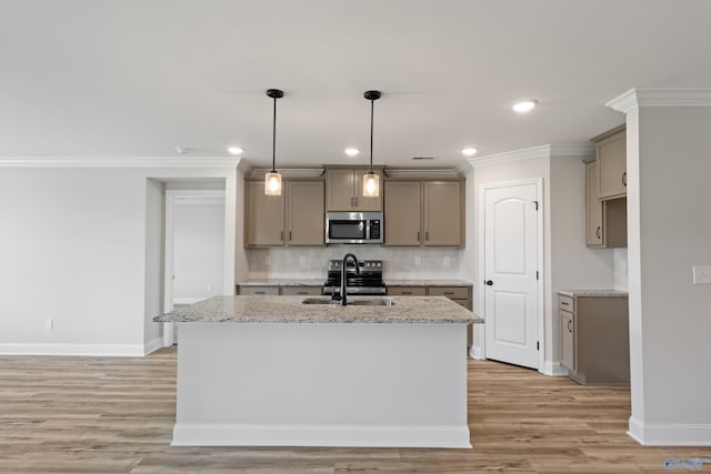 kitchen with a center island with sink, light wood-type flooring, decorative backsplash, appliances with stainless steel finishes, and sink