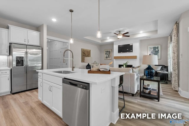 kitchen featuring appliances with stainless steel finishes, sink, light hardwood / wood-style floors, and a tray ceiling