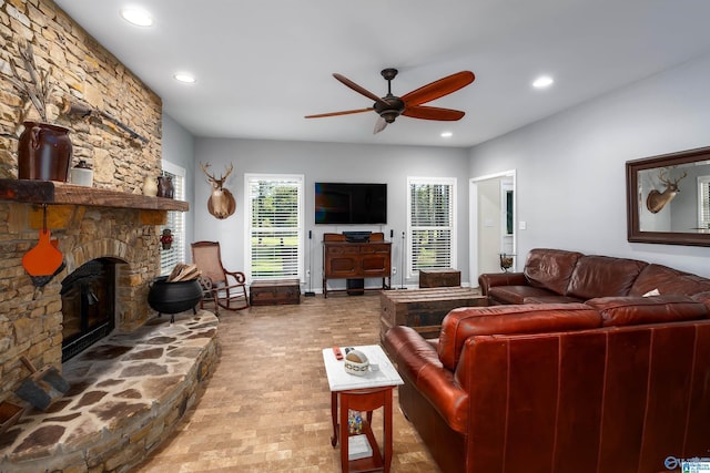 living room featuring ceiling fan and a stone fireplace