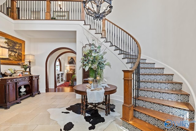 3127 Haddonstone Dr SE, Owens Cross Roads, AL 35763 - stairs featuring arched walkways, a towering ceiling, a chandelier, baseboards, and tile patterned floors