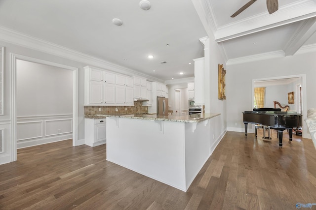 kitchen featuring freestanding refrigerator, a breakfast bar, light stone countertops, dark wood-style floors, and white cabinetry