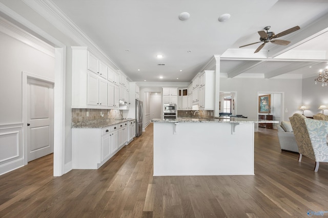 kitchen featuring a peninsula, open floor plan, a breakfast bar area, light stone counters, and stainless steel appliances