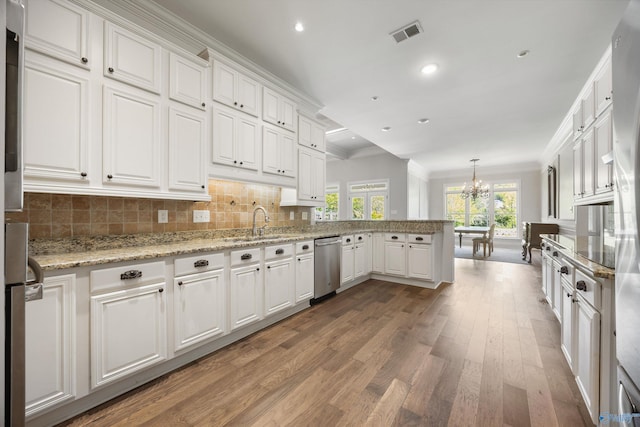 kitchen featuring white cabinets, a notable chandelier, light wood-style floors, dishwasher, and a peninsula