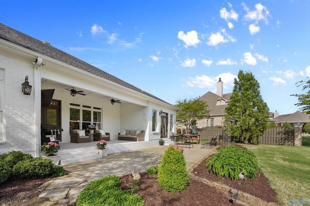 back of property featuring an outdoor living space, a ceiling fan, fence, a yard, and a patio