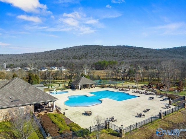 pool with a forest view, fence, and a patio area