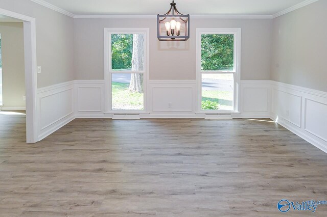 unfurnished dining area featuring a healthy amount of sunlight, an inviting chandelier, and hardwood / wood-style floors