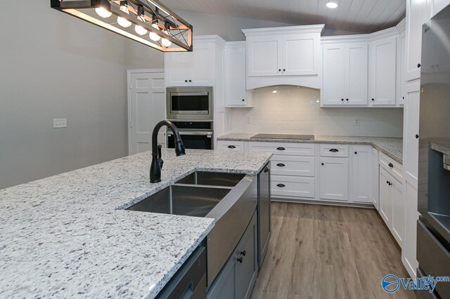 kitchen with pendant lighting, white cabinetry, tasteful backsplash, stainless steel appliances, and wood finished floors