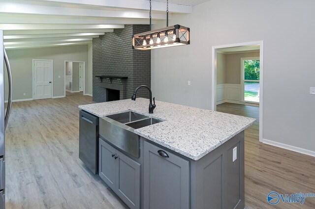 kitchen with a fireplace, light wood-type flooring, dishwasher, lofted ceiling with beams, and a center island with sink