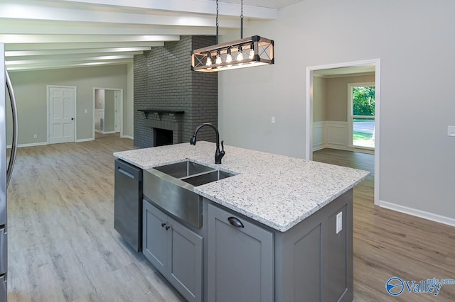 kitchen featuring gray cabinets, light wood-style flooring, dishwasher, a sink, and open floor plan
