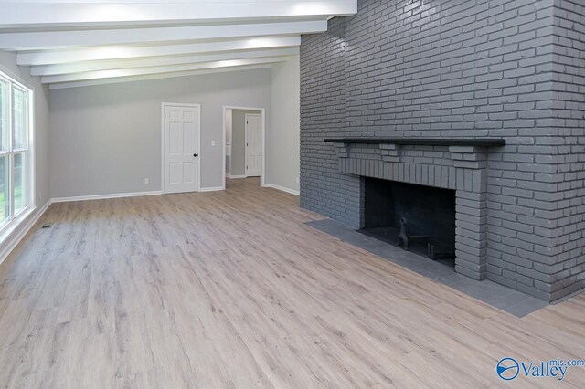 unfurnished living room featuring light hardwood / wood-style floors, a brick fireplace, and lofted ceiling with beams