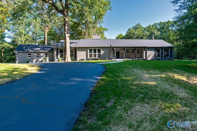 single story home featuring a front lawn, driveway, and a chimney