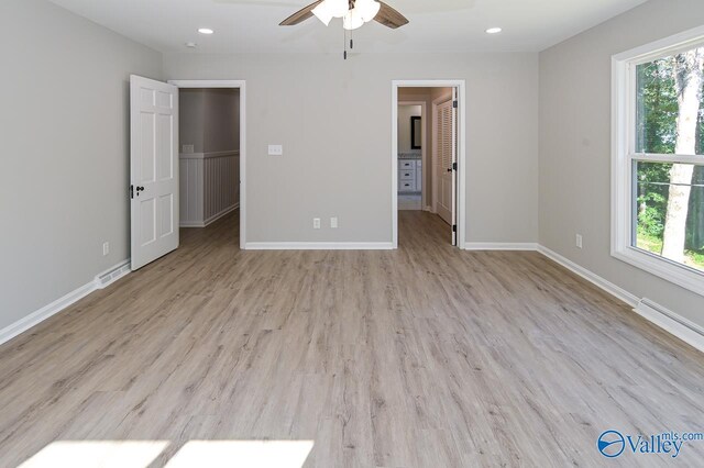 unfurnished bedroom featuring a spacious closet, multiple windows, and light wood-type flooring