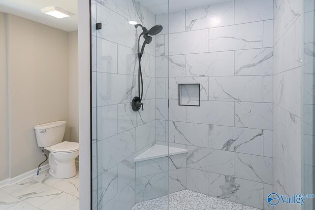 bathroom featuring tile patterned flooring, toilet, and a tile shower