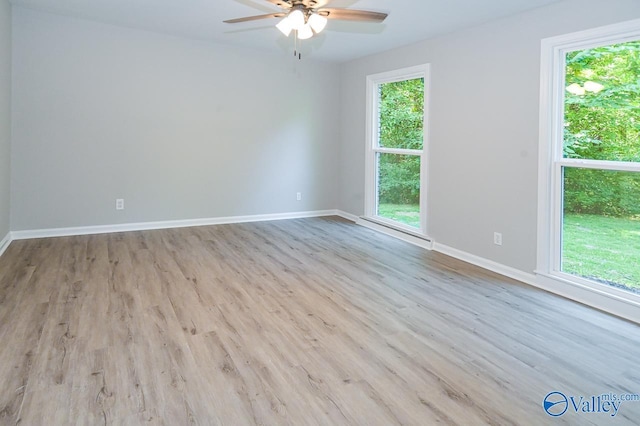 empty room with baseboards, wood finished floors, and a ceiling fan