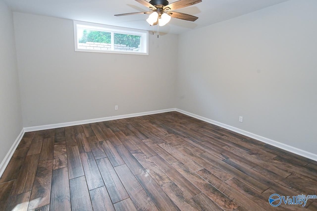 spare room featuring dark wood-type flooring, a ceiling fan, and baseboards