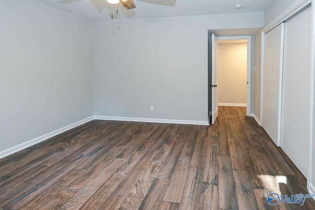 unfurnished bedroom with dark wood-style floors, a closet, and baseboards