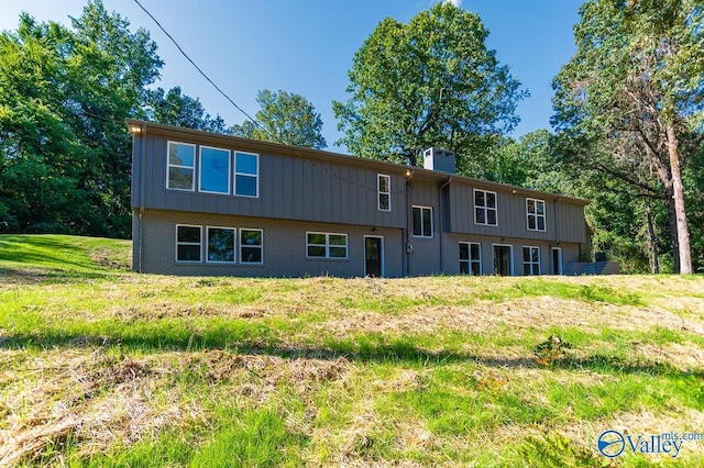 back of property featuring brick siding, board and batten siding, and a chimney