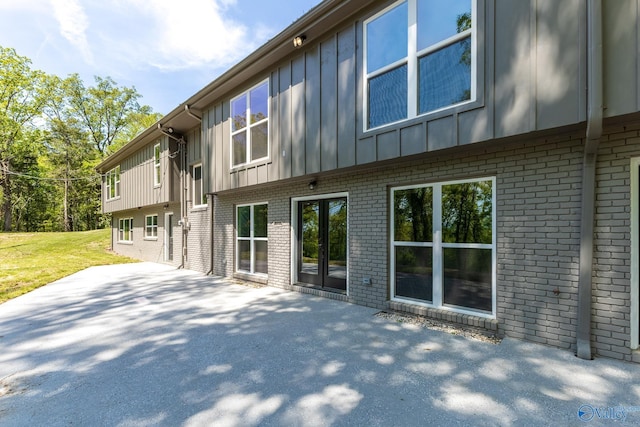 rear view of house with a patio area, board and batten siding, and brick siding