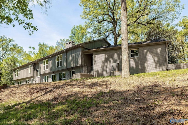 exterior space with a chimney, board and batten siding, and brick siding