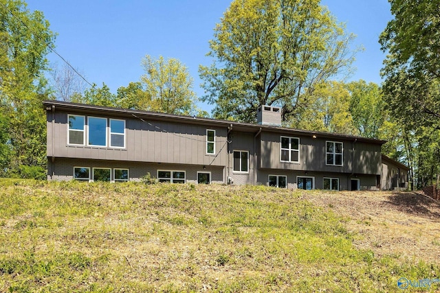 rear view of property with a chimney and brick siding