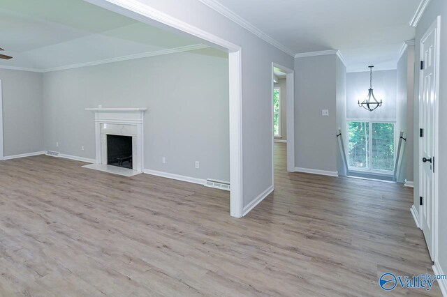 unfurnished living room with a premium fireplace, a notable chandelier, hardwood / wood-style floors, and ornamental molding