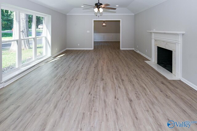 unfurnished living room featuring lofted ceiling, light hardwood / wood-style flooring, ceiling fan, a fireplace, and ornamental molding