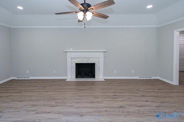 unfurnished living room featuring a high end fireplace, crown molding, ceiling fan, and hardwood / wood-style floors