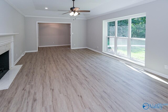 unfurnished living room featuring a premium fireplace, a wealth of natural light, ceiling fan, and light hardwood / wood-style flooring