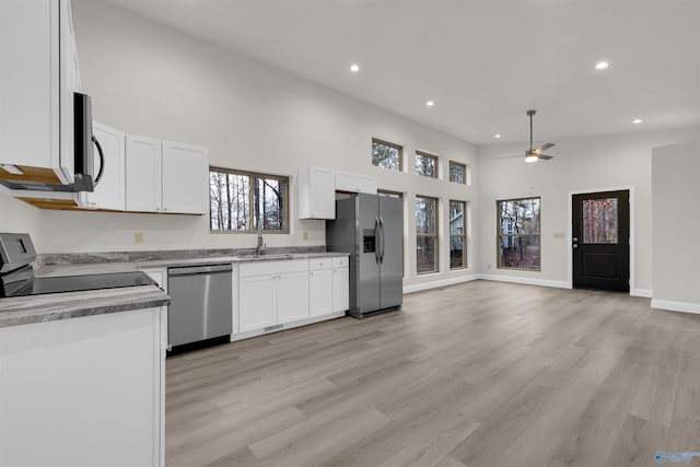 kitchen with appliances with stainless steel finishes, ceiling fan, sink, white cabinets, and light hardwood / wood-style floors