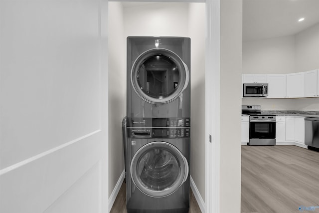 laundry area featuring stacked washer and dryer and light wood-type flooring