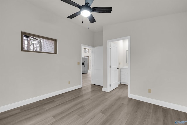 unfurnished bedroom featuring stainless steel fridge, light hardwood / wood-style flooring, ensuite bath, and ceiling fan