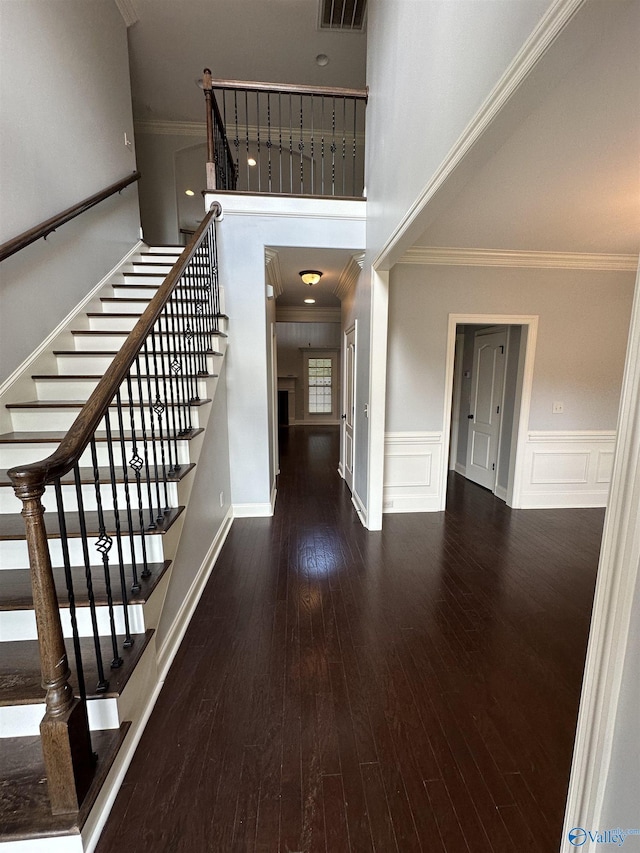 staircase featuring hardwood / wood-style floors, a towering ceiling, and crown molding