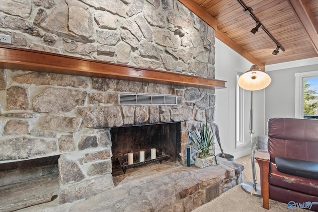 living room with beam ceiling, rail lighting, a stone fireplace, and wood ceiling