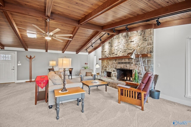 living room with ceiling fan, rail lighting, vaulted ceiling with beams, light carpet, and a fireplace