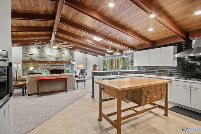 kitchen featuring dishwasher, a stone fireplace, gas stovetop, tasteful backsplash, and white cabinetry