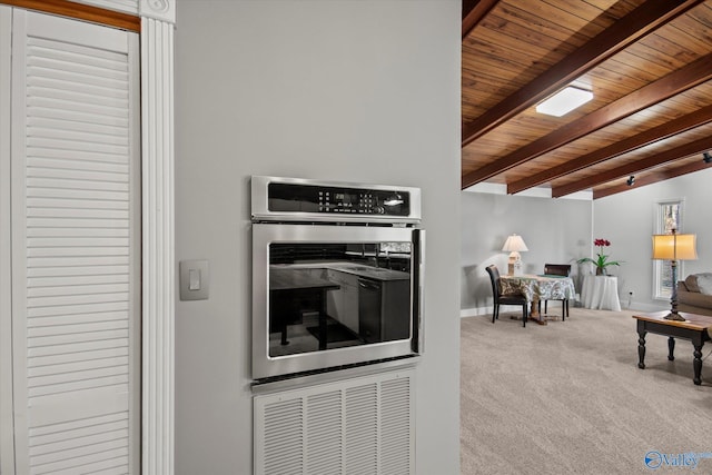 kitchen with vaulted ceiling with beams, carpet floors, stainless steel double oven, and wood ceiling