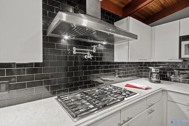 kitchen with white cabinets, wall chimney exhaust hood, backsplash, and stainless steel appliances