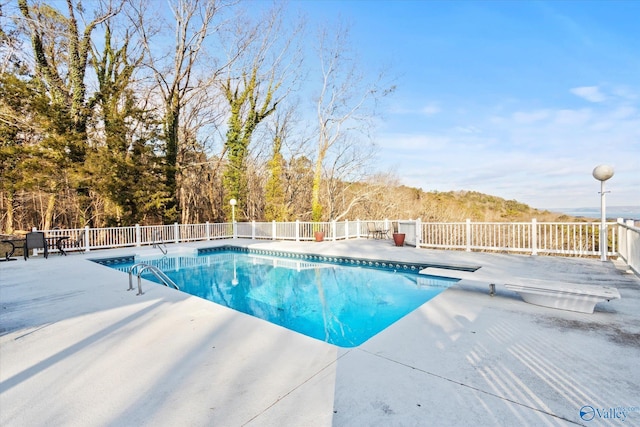 view of pool with a diving board and a patio area