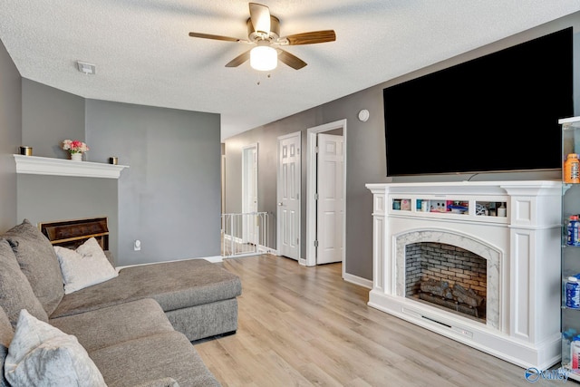 living area with light wood-style flooring, visible vents, a textured ceiling, and a high end fireplace