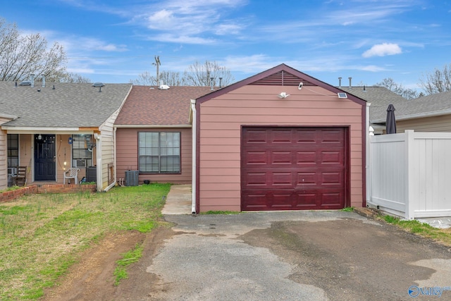 garage with aphalt driveway, fence, and central air condition unit