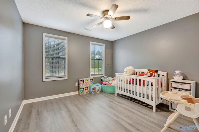 bedroom featuring baseboards, visible vents, ceiling fan, wood finished floors, and a textured ceiling