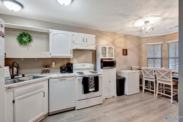 kitchen featuring white appliances, light wood-type flooring, a sink, and white cabinetry